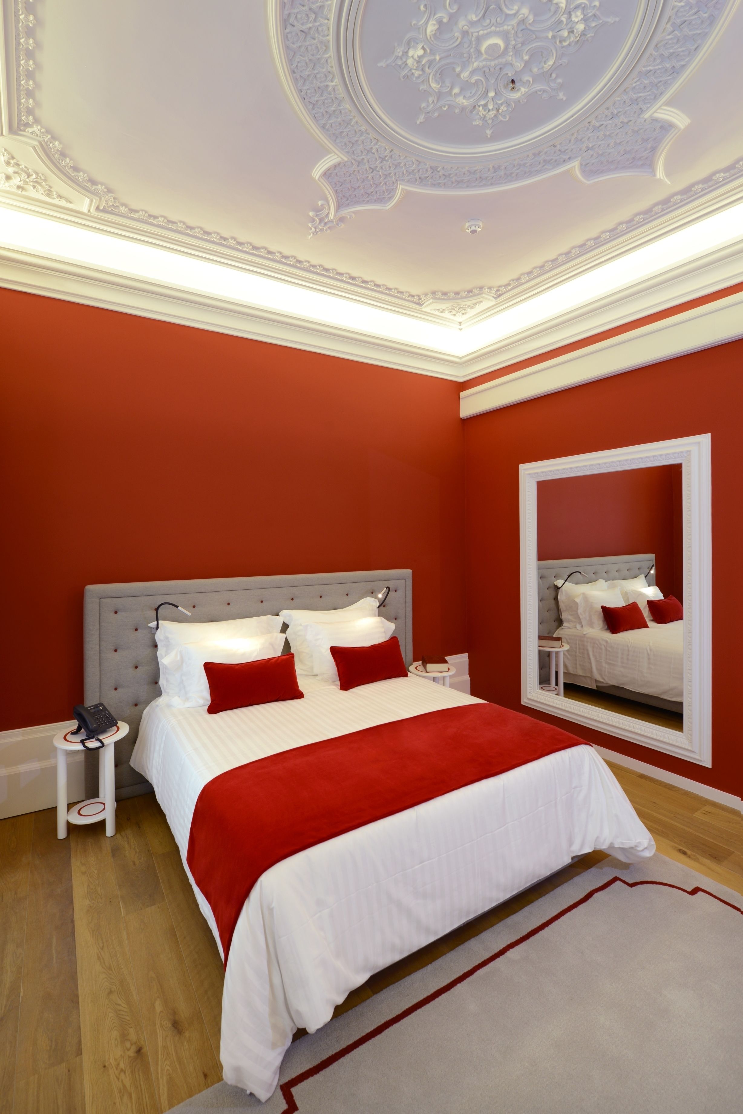 A bedroom with a large bed, a bedside table, a mirror, and a telephone.