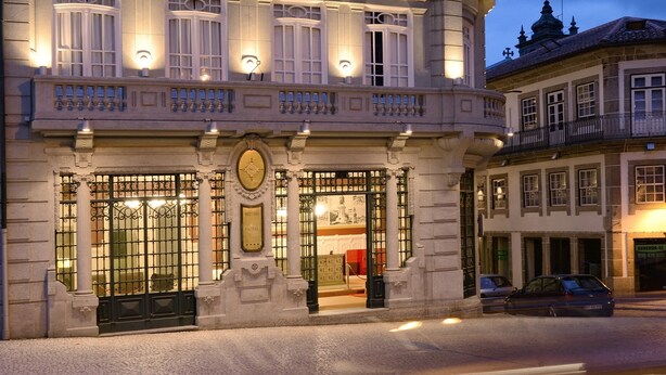 Ein historisches Gebäude mit einer Uhr, verzierten Balkonen und einer Kopfsteinpflasterstraße.