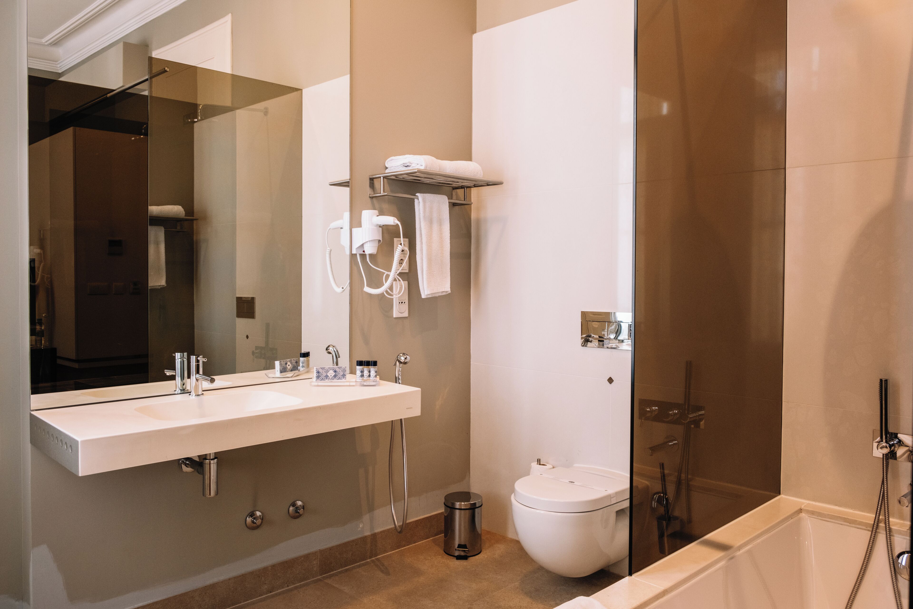 A modern bathroom with two sinks, a toilet, a shower, and a large mirror.