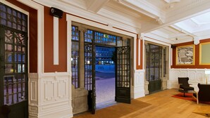 Eine geräumige Lobby mit Holzboden, einer großen offenen Tür nach draußen und einem gerahmten Bild an der Wand.