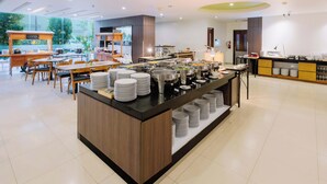 A modern buffet setup with multiple serving stations, a central island with stacked plates, and a clean, well-lit interior. - favehotel Hyper Square (Bandung)