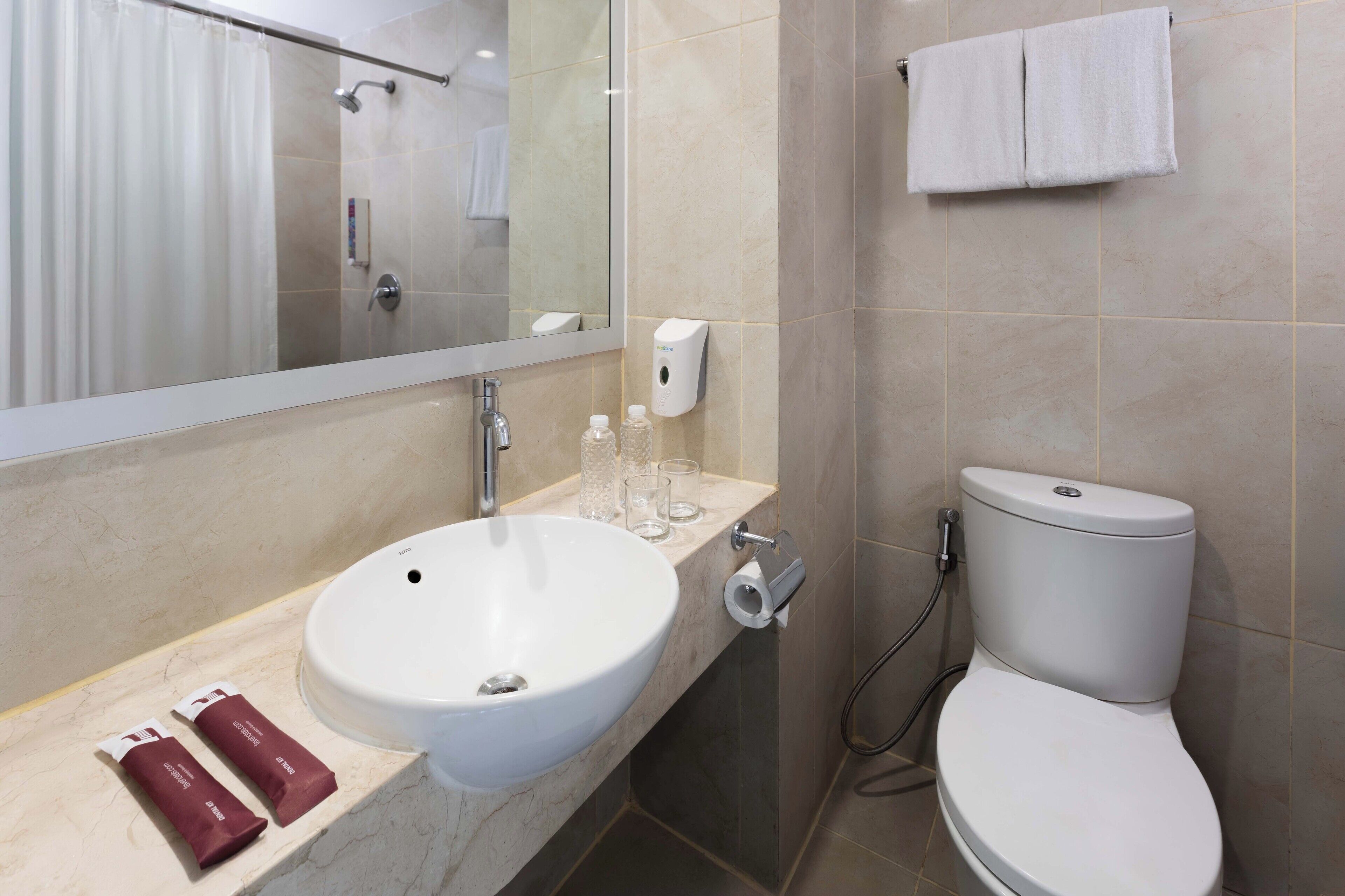 Un baño moderno con lavamanos, espejo y retrete blancos.