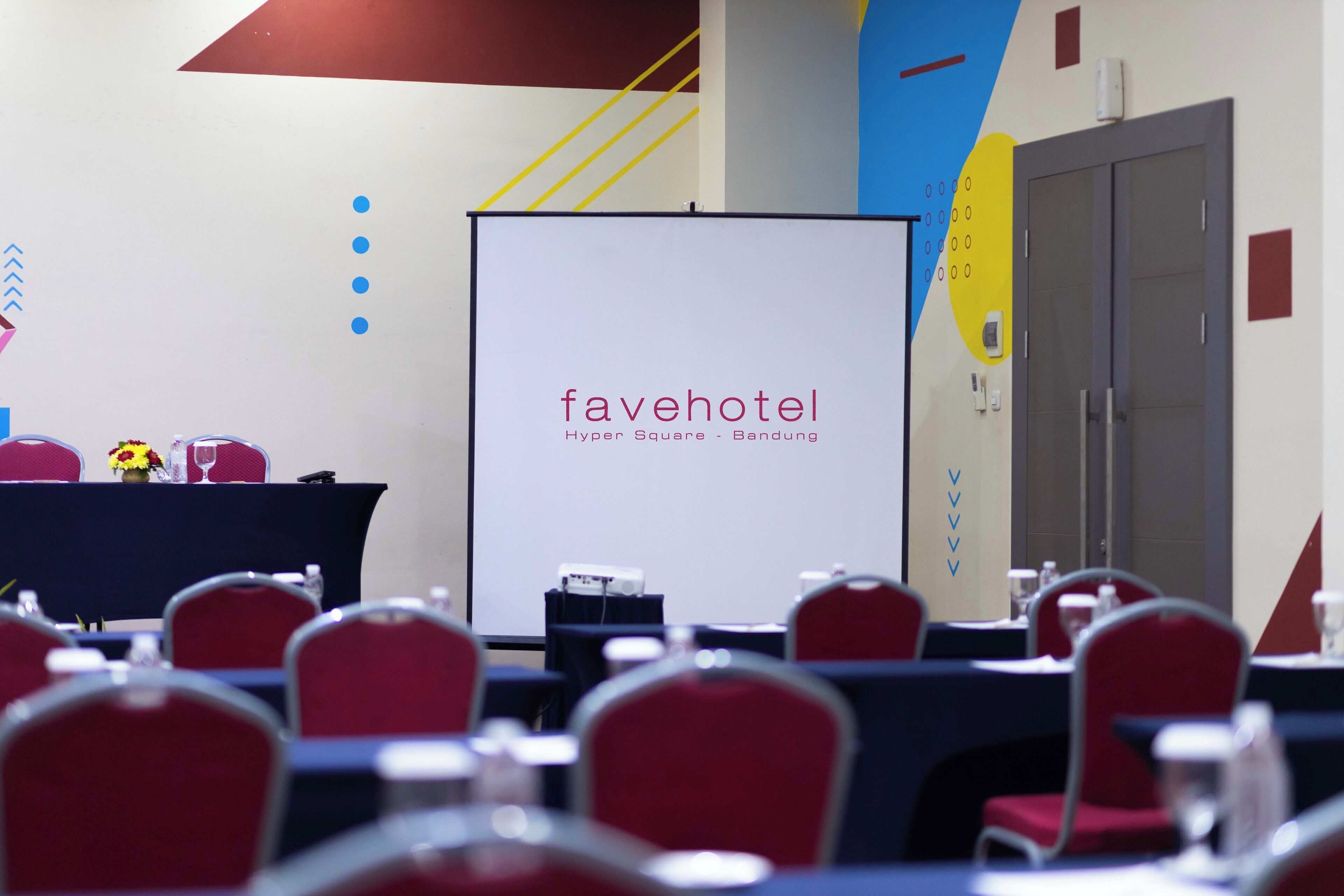 Uma sala de conferências com uma tela de projeção exibindo 'favehotel Hyper Square - Bandung'.