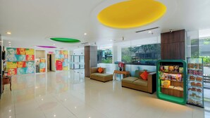 A modern lobby with a glass wall, a seating area with sofas, a snack kiosk, and colorful wall art. - favehotel Hyper Square (Bandung)