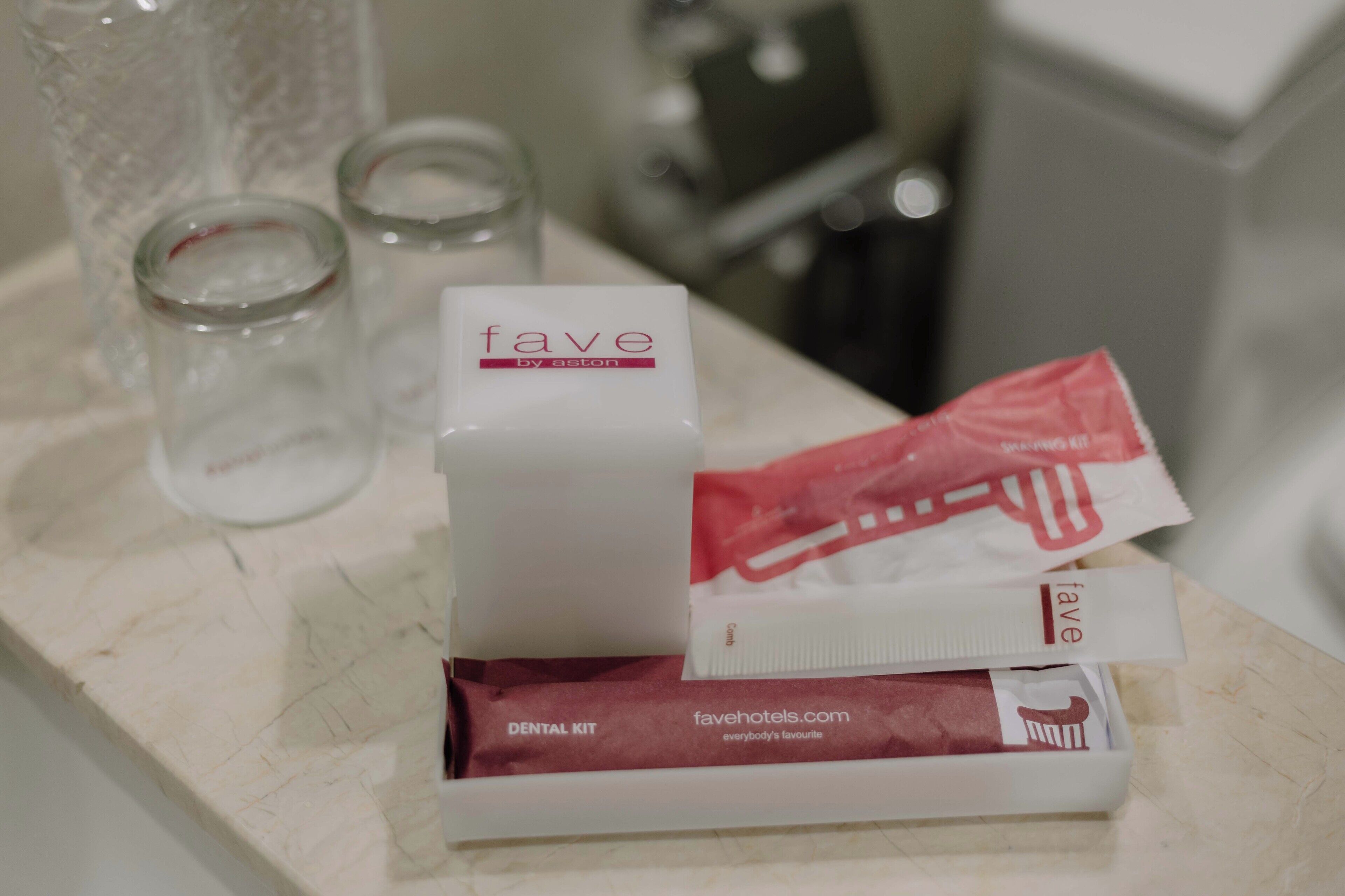 A bathroom counter with a dental kit, a glass, and a toothbrush.