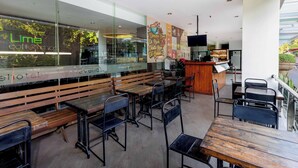 A modern cafe with wooden benches and tables, a counter with a menu, and a view of the outdoors. - favehotel Hyper Square (Bandung)