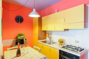 A kitchen with yellow cabinets, a white countertop, a stove, and a microwave. - Patty's Aparthotel Arezzo (Arezzo)