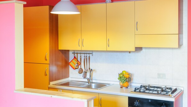 A kitchen with yellow cabinets, a white sink, and a gas stove. - Patty's Aparthotel Arezzo (Arezzo)
