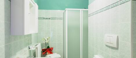 A bathroom with a sink, mirror, and shower.