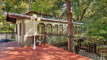 Un espacio al aire libre techado con una terraza de madera, una farola y una barandilla.