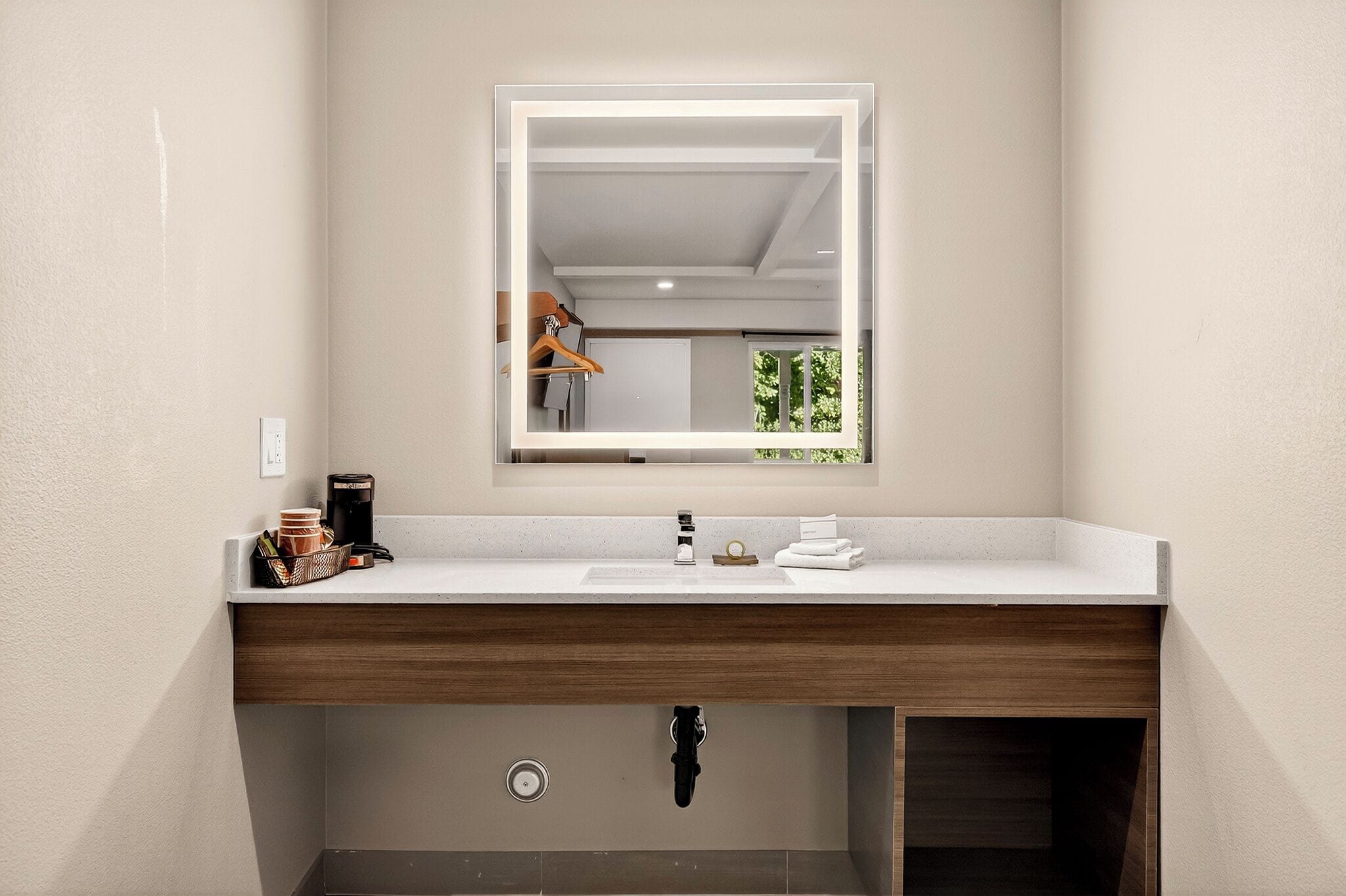 Een badkamer met een wit wastafel, een spiegel en een houten wastafelmeubel.