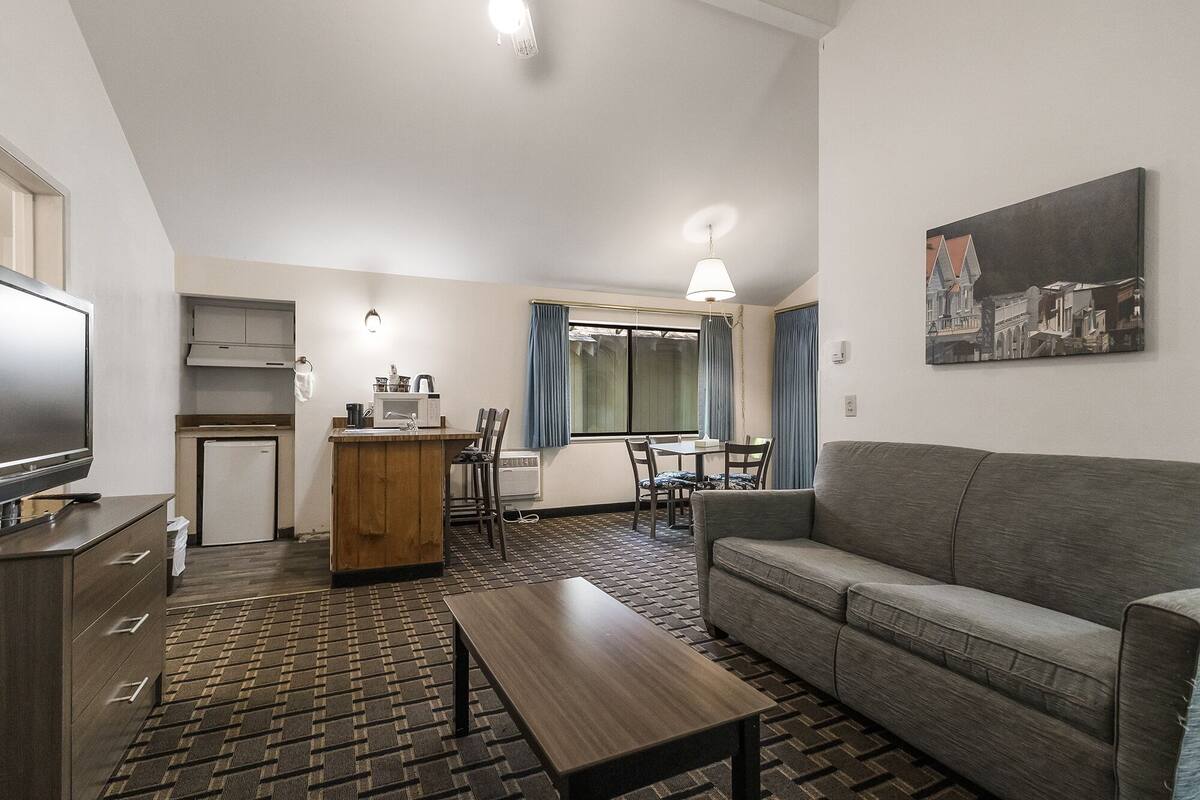 A compact living space with a kitchenette, a dining area, and a seating area with a sofa and a coffee table.