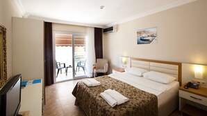 Une chambre d’hôtel équipée d’un lit, d’un bureau, d’une chaise, d’une télévision et d’un balcon avec des chaises.