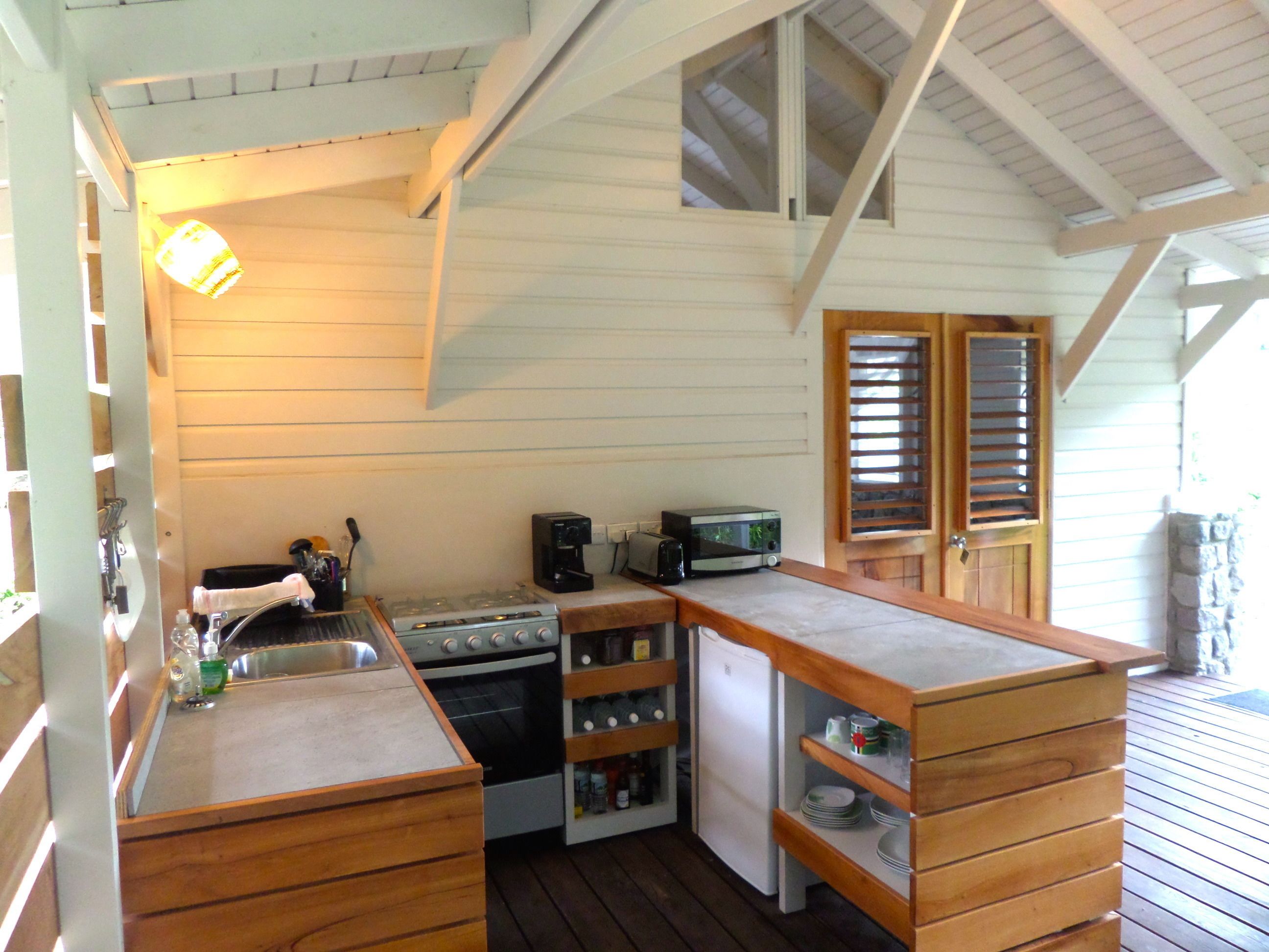 A compact kitchen with wooden cabinets, a sink, a stove, a microwave, and a refrigerator.