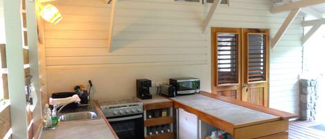 A compact kitchen with wooden cabinets, a sink, a stove, a microwave, and a refrigerator.