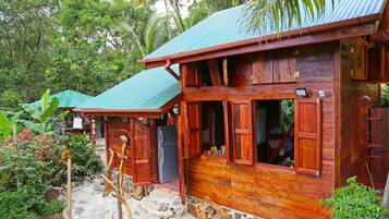 Situated in a lush garden, this cabin offers a peaceful retreat with a stone-paved entrance and a charming wooden porch.