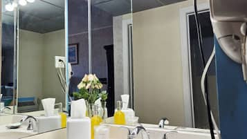 A bathroom with a large mirror, two sinks, and a hairdryer on the counter.