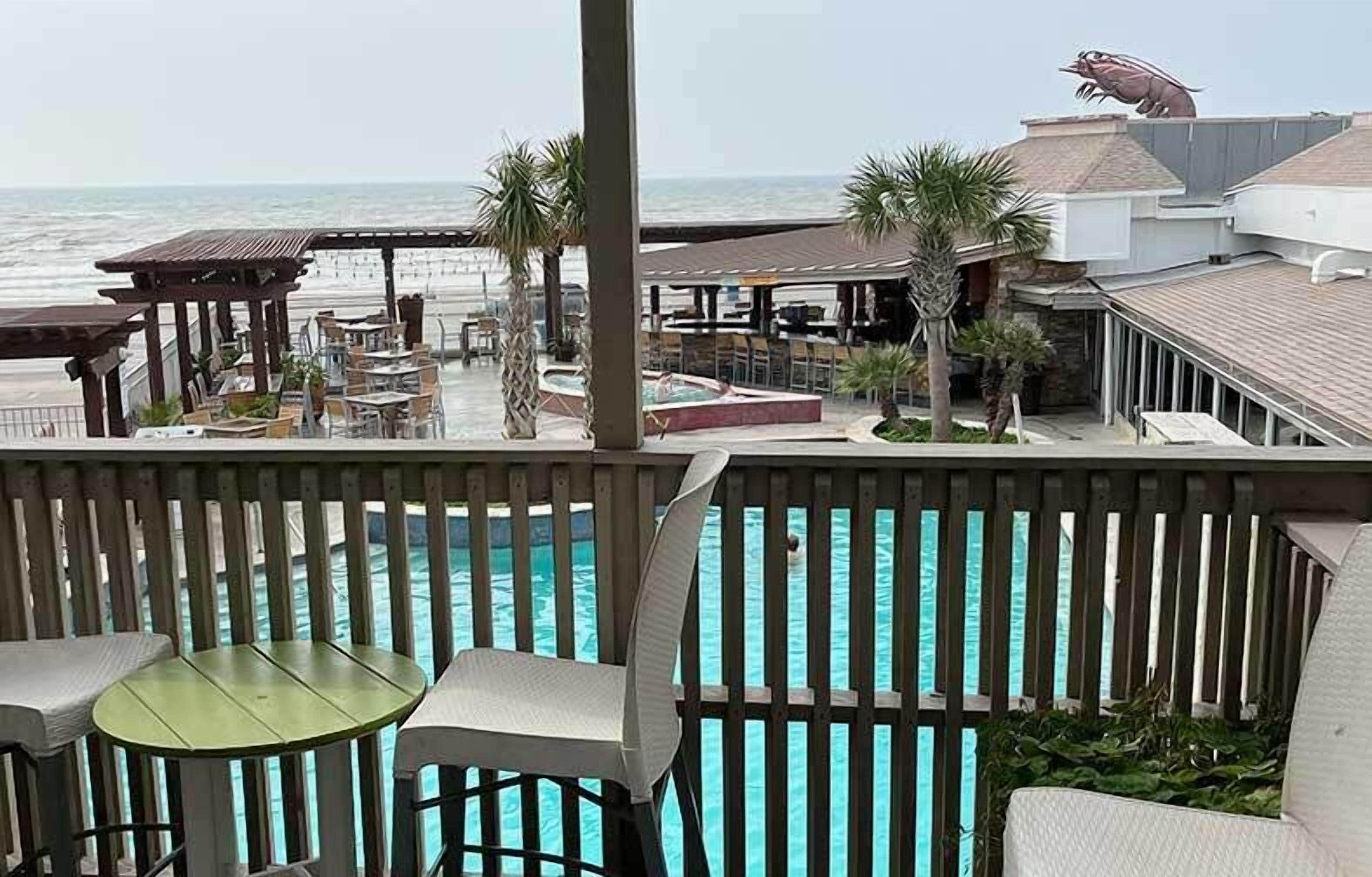 A poolside area with a view of the ocean, outdoor seating, and a lifeguard tower.