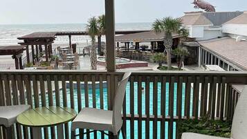 A poolside area with a view of the ocean, outdoor seating, and a lifeguard tower.