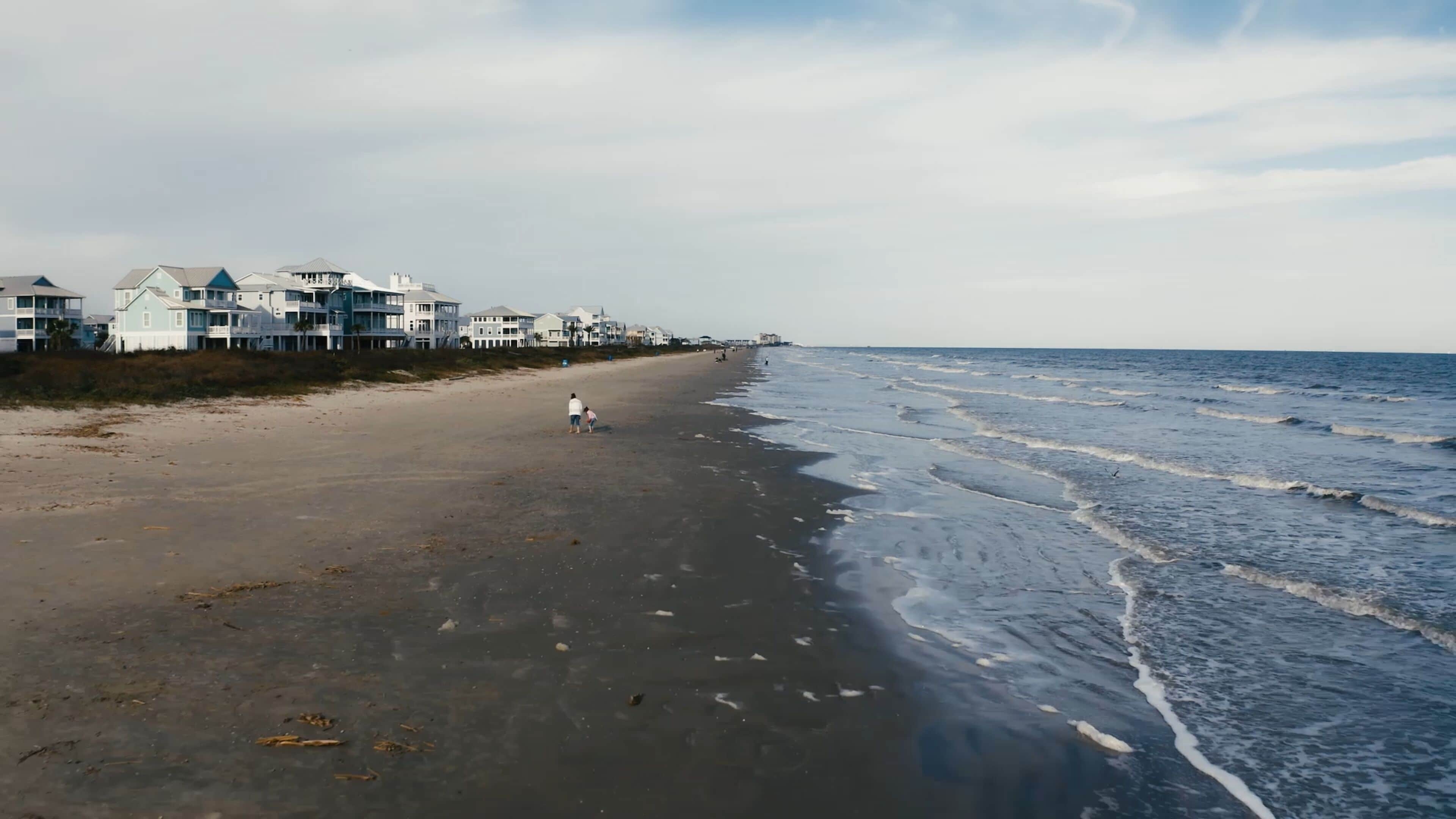 A beach with a row of houses along the shore.