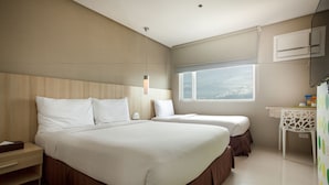 Habitación de hotel con una cama grande, una mesita de noche, un escritorio pequeño y una ventana con vistas.