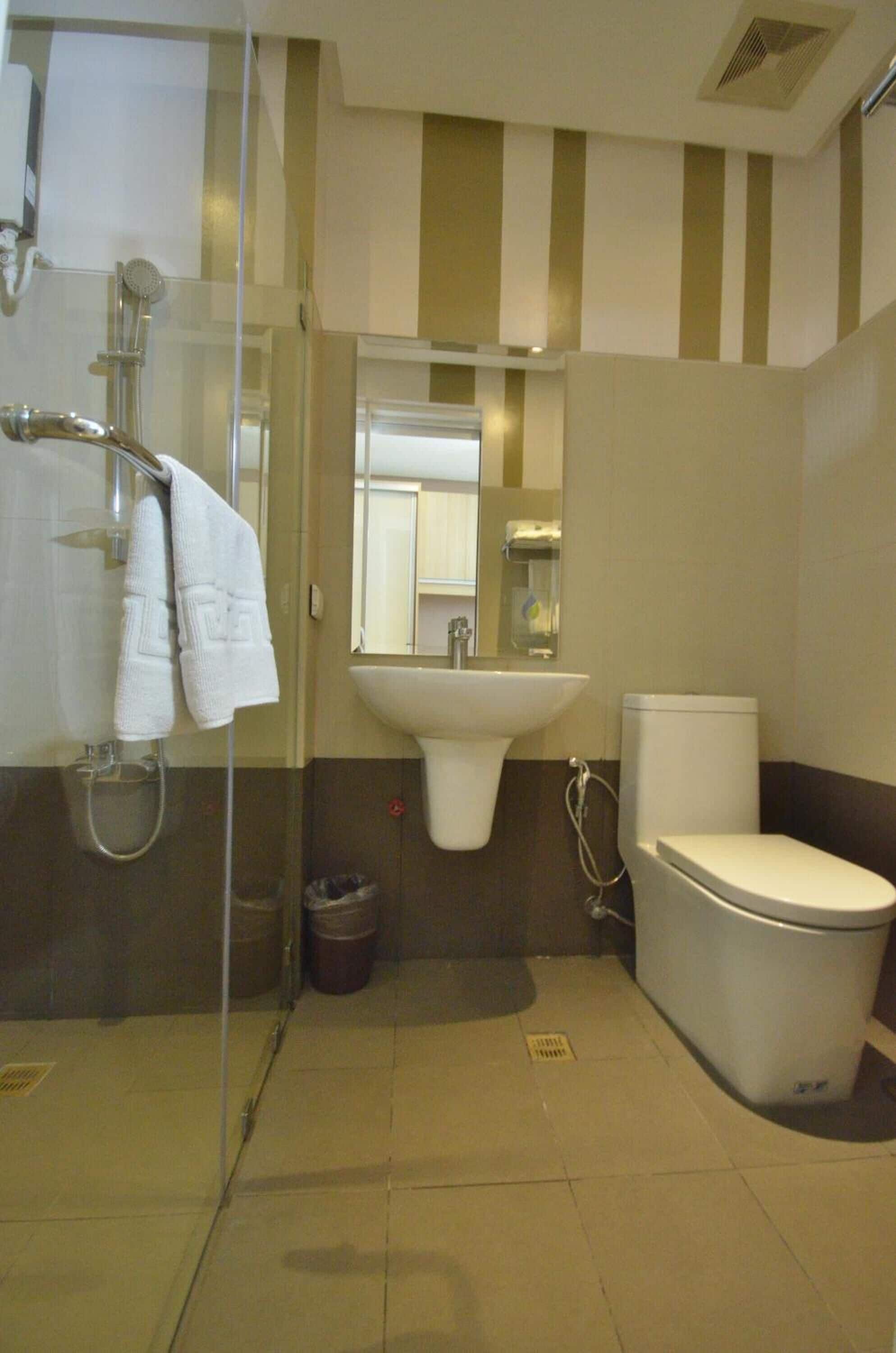 Un baño con cabina de ducha de vidrio, lavabo e inodoro.