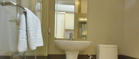 A bathroom with a glass shower enclosure, a sink, and a toilet.