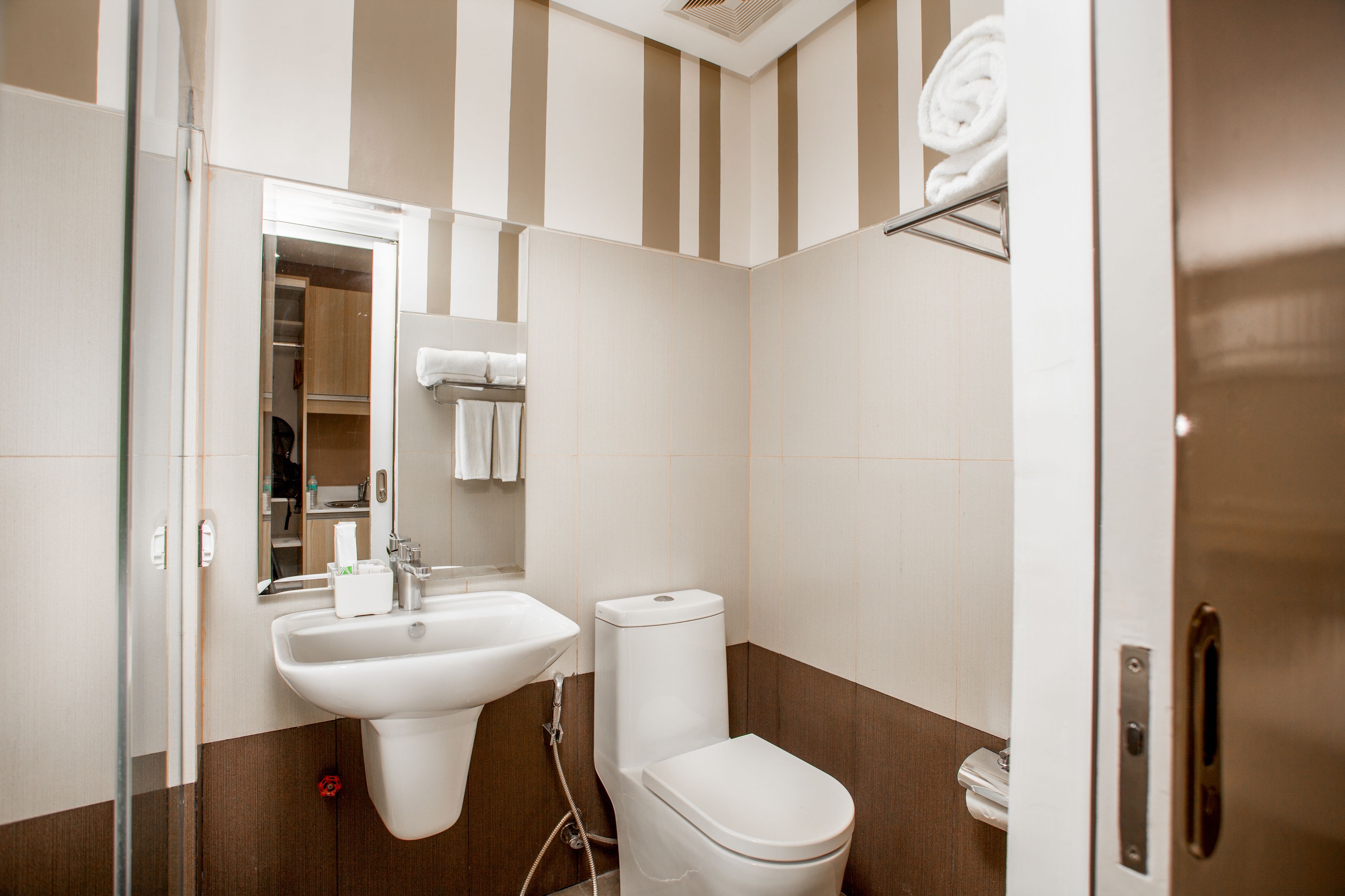 A modern bathroom with a sink, toilet, and a mirror.