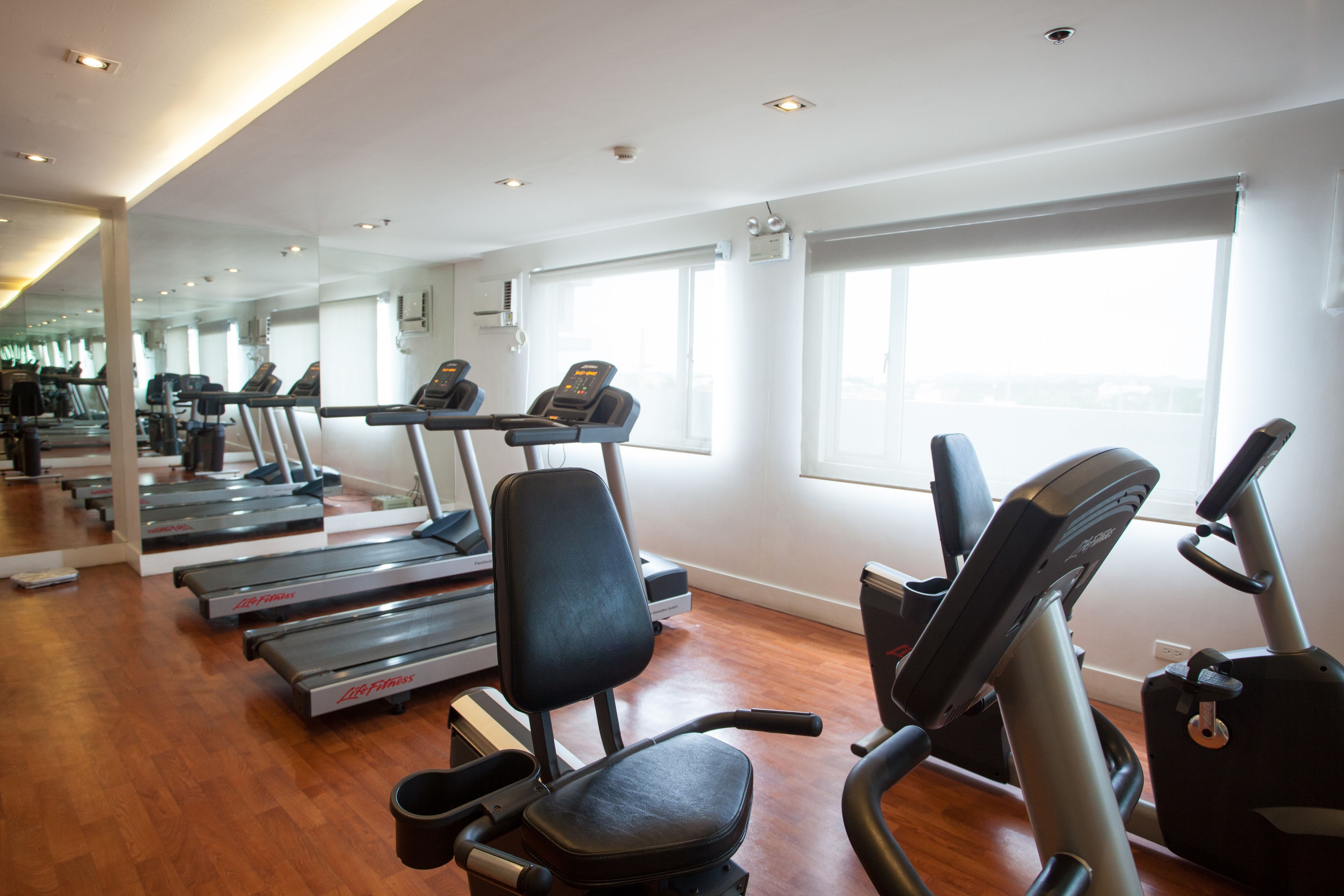 A gym with treadmills, exercise bikes, and a mirrored wall.