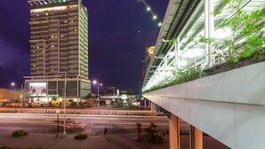 A high-rise building with multiple floors, a pedestrian walkway, and a construction crane in the background.