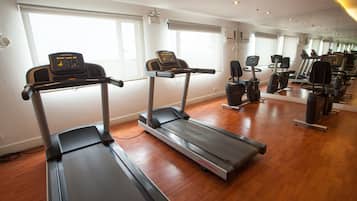 A gym with treadmills, exercise bikes, and a mirrored wall.