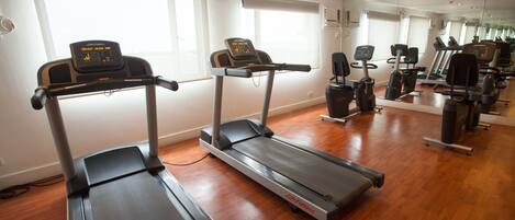 A gym with treadmills, exercise bikes, and a mirrored wall.