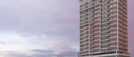 A multi-story hotel with a modern design, located near a busy street with cars and pedestrians.
