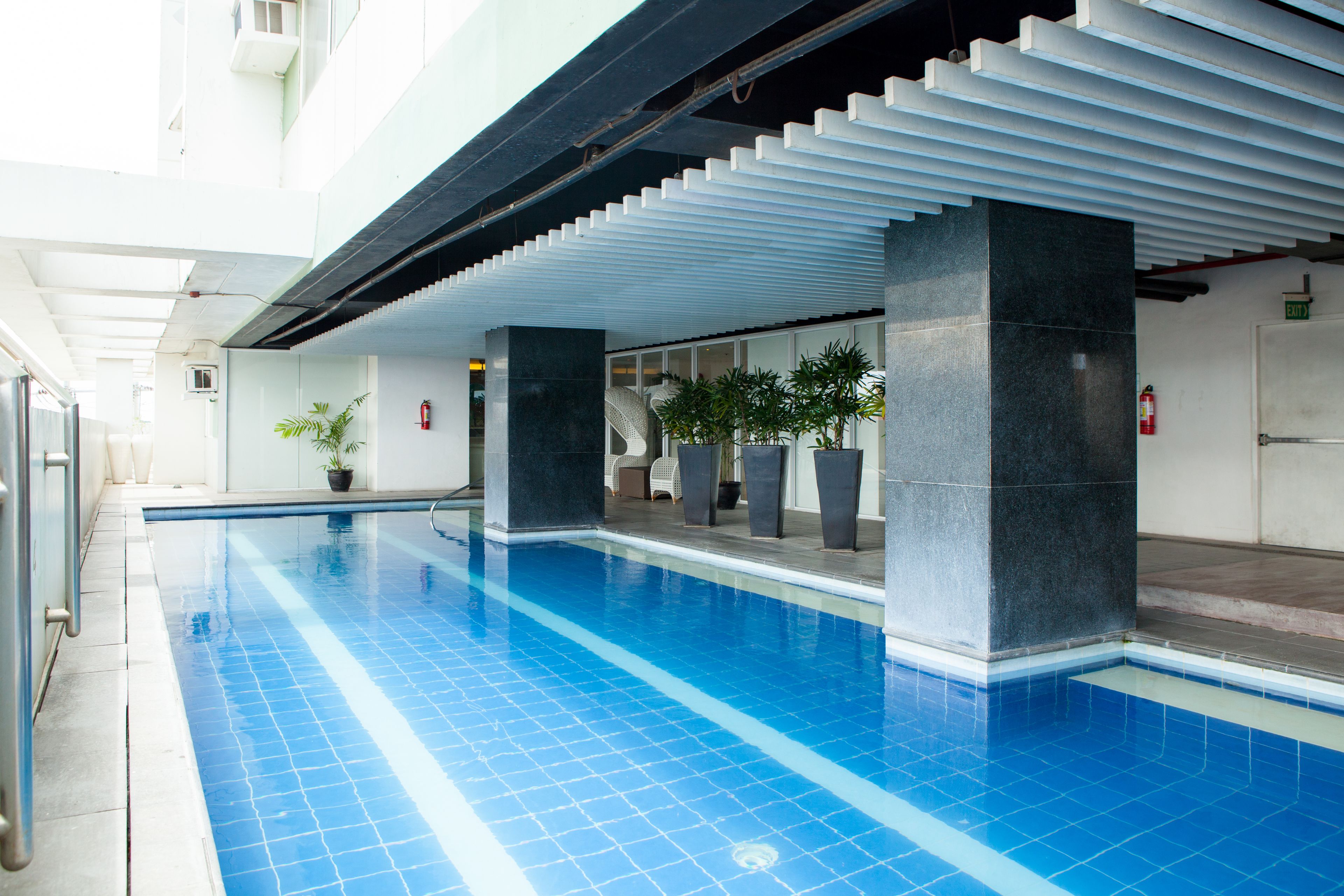A swimming pool with blue tiles, white walls, and black pillars.