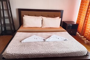 Una cama con una colcha estampada, dos almohadas, una mesita de noche y una lámpara.