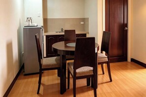 Un comedor pequeño con una mesa redonda y cuatro sillas, una kitchenette compacta y una puerta de madera.