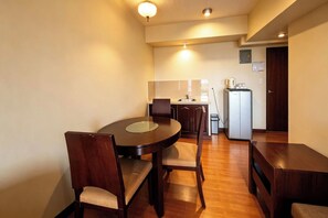 Un espacio comedor compacto con una mesa redonda, sillas, un refrigerador y una pequeña kitchenette.