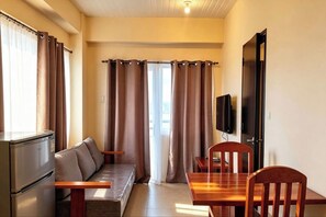 A compact living space with a kitchenette, a sofa, a dining table, and a television.