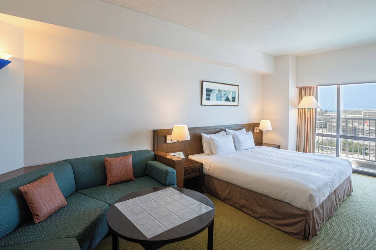 Une chambre d’hôtel avec un lit, un canapé, une petite table et une table de chevet.
