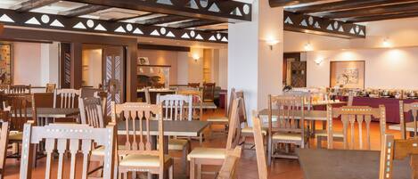 Un restaurante con mobiliario de madera y un techo alto con vigas a la vista.
