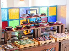 A buffet table with various dishes and bowls, set against a colorful window backdrop.