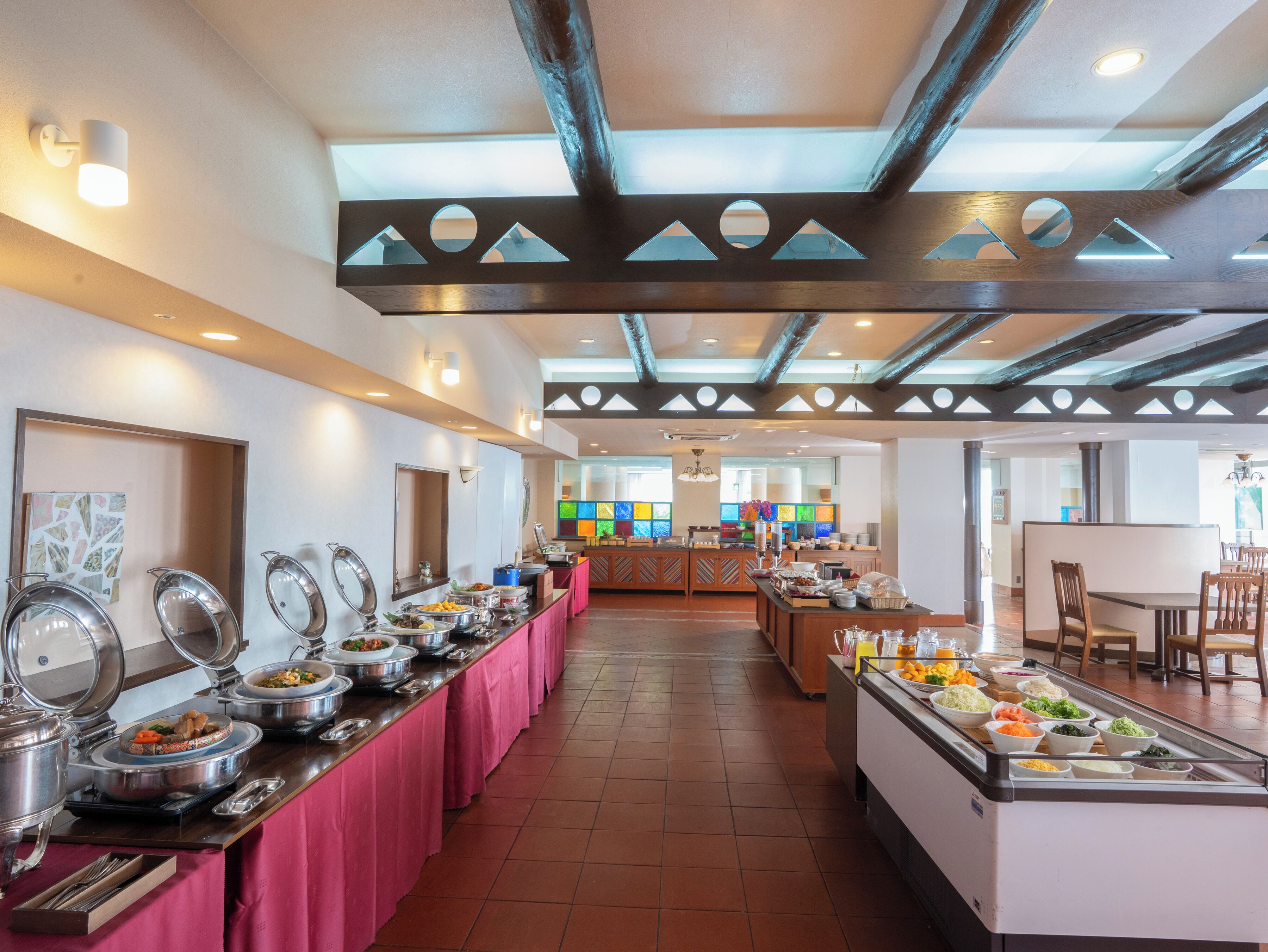 A buffet setup with multiple serving stations, a central island, and a dining area with chairs and tables.