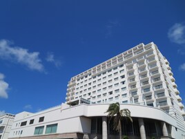 Un hotel moderno de gran altura con fachada blanca, varios balcones y una sección inferior curva.