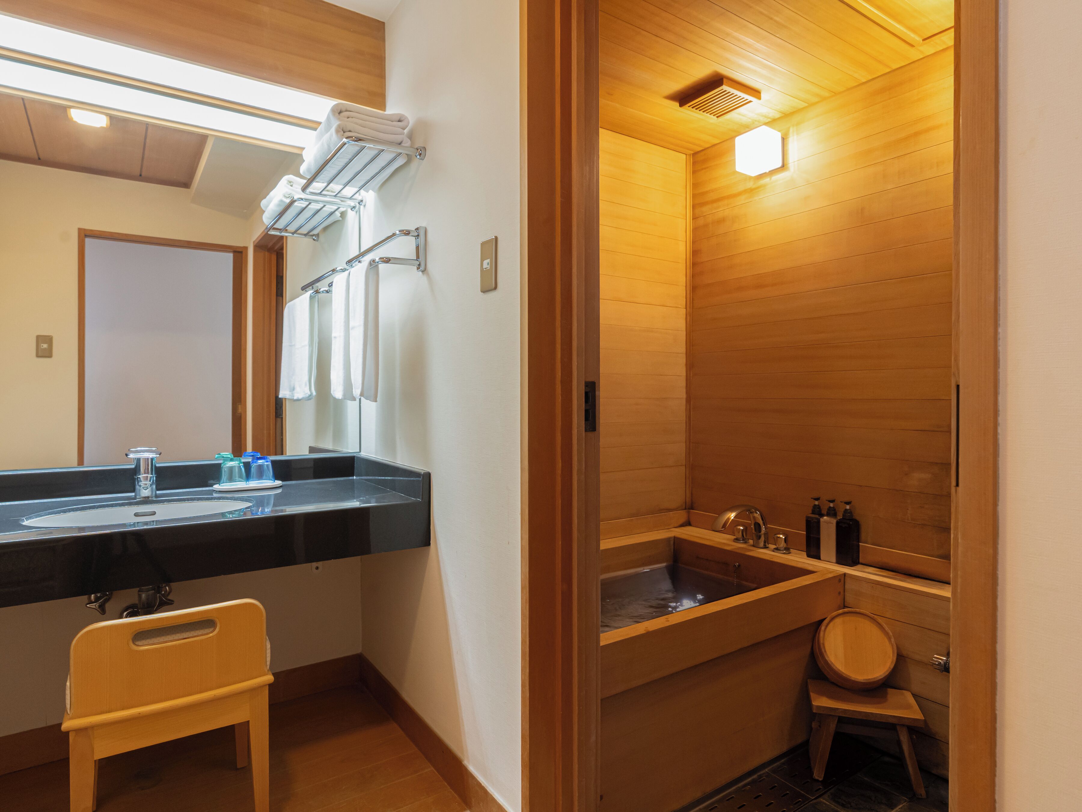 A modern bathroom with a wooden vanity, a sink, and a separate shower area.