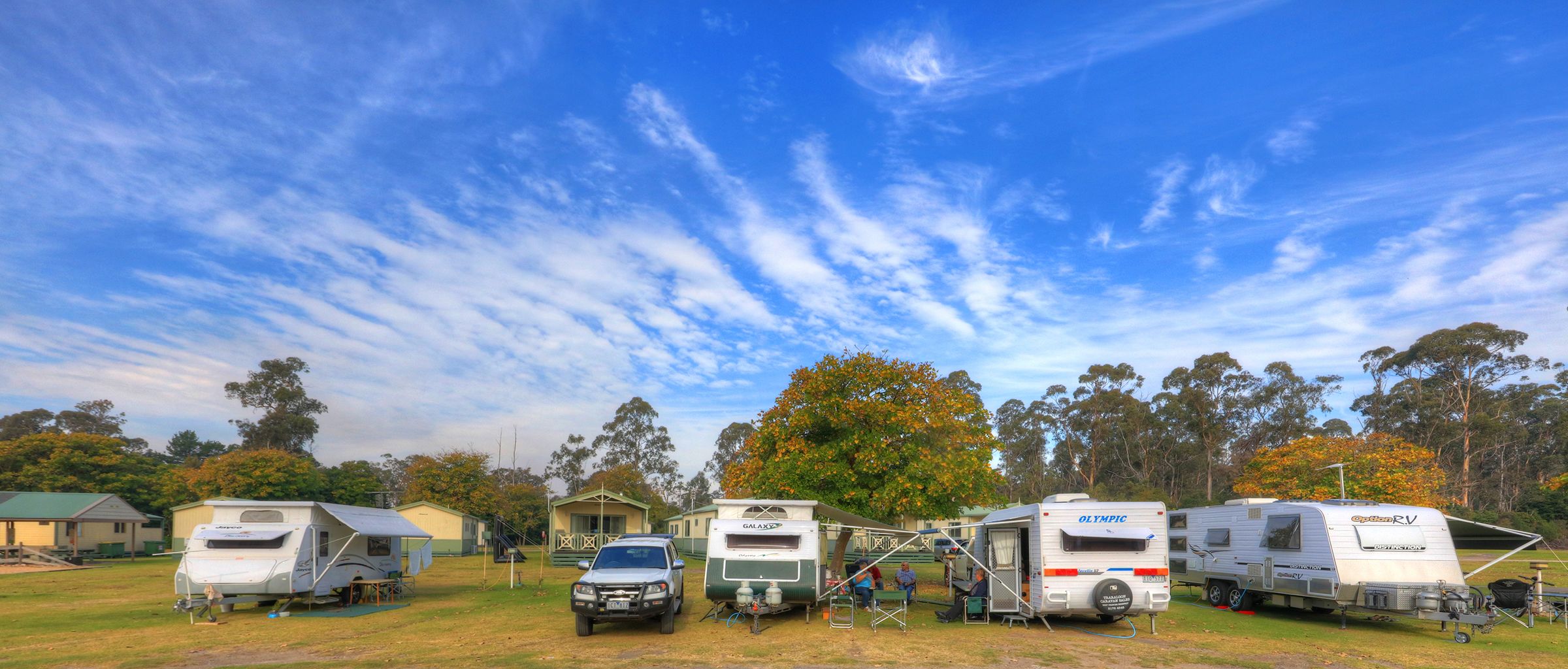 A campsite with RVs and a small building.