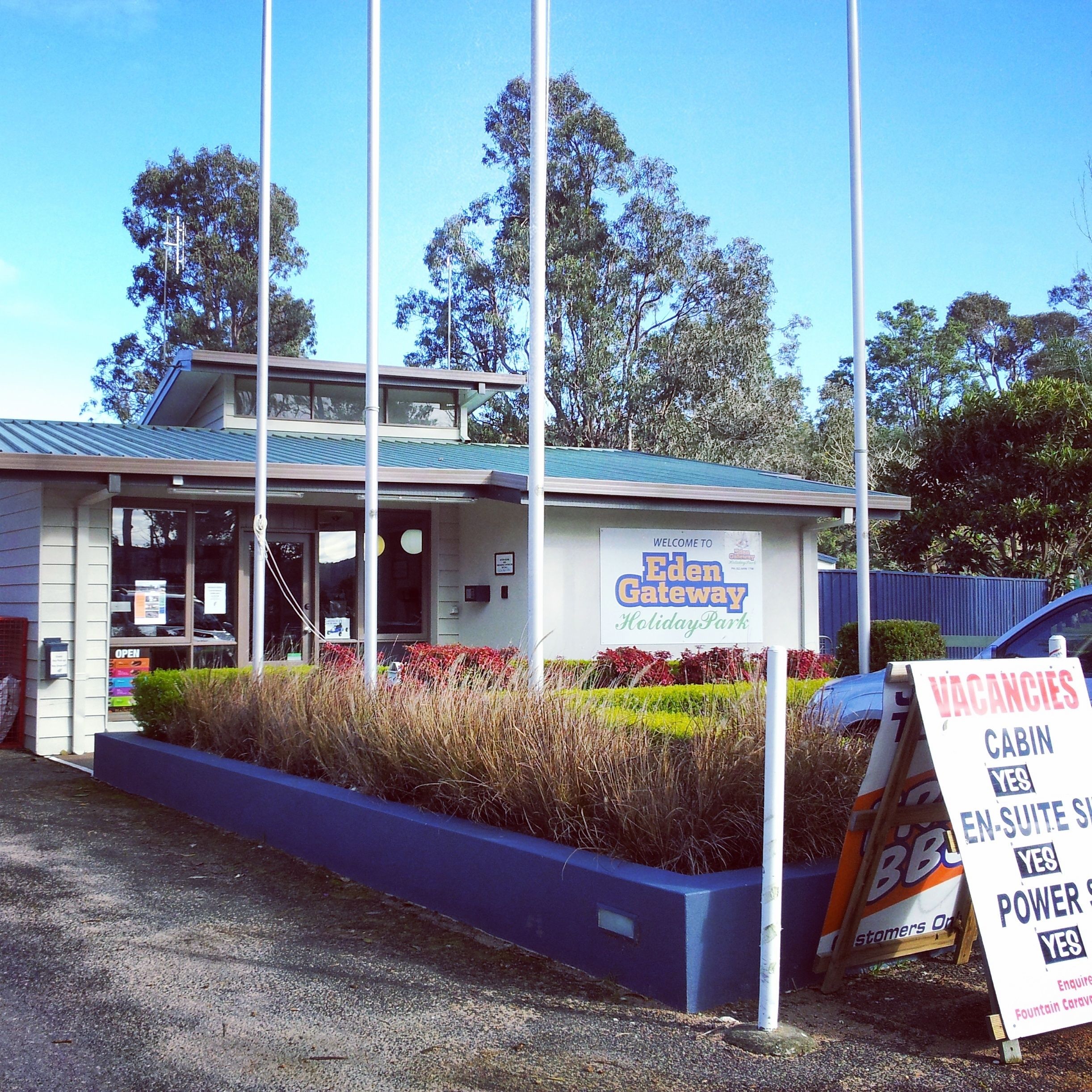 A building labeled 'Eden Gateway Holiday Park' with a sign indicating vacancies for cabins and power.