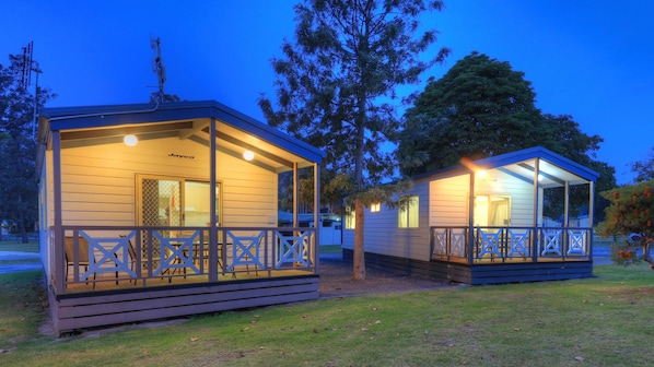 Two small, single-story cabins with attached porches, each featuring a small deck and a covered seating area.