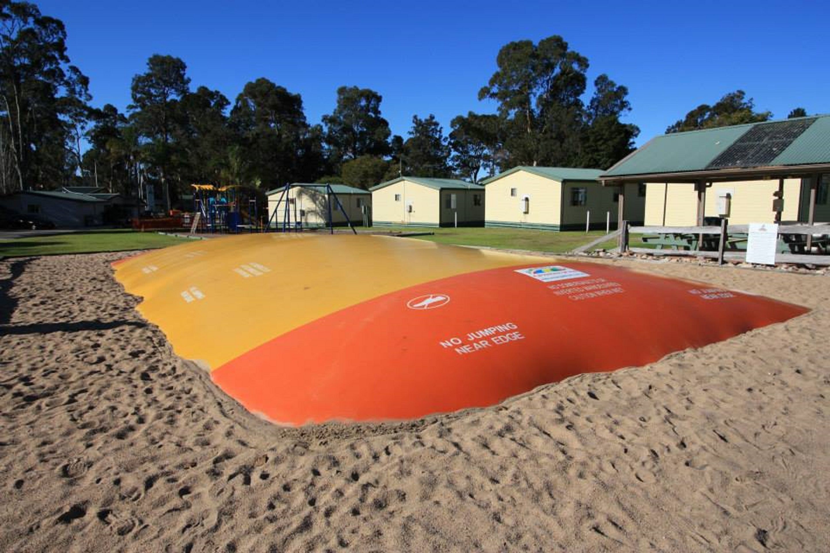 A beach with a safety zone marked by a red and yellow mat with a no-jumping warning.