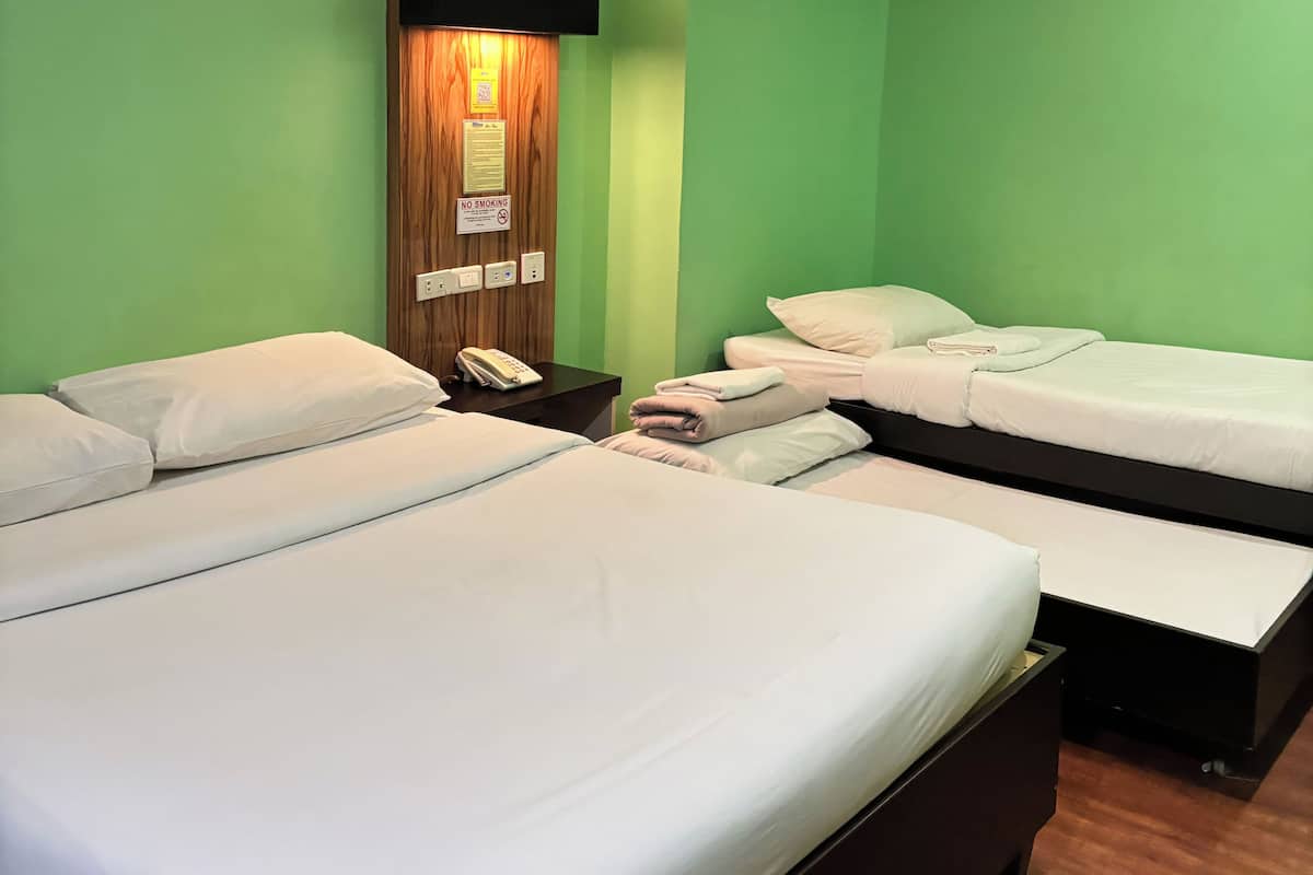 A hotel room with two beds, a wooden wall panel, a phone on the nightstand, and a 'No Smoking' sign.
