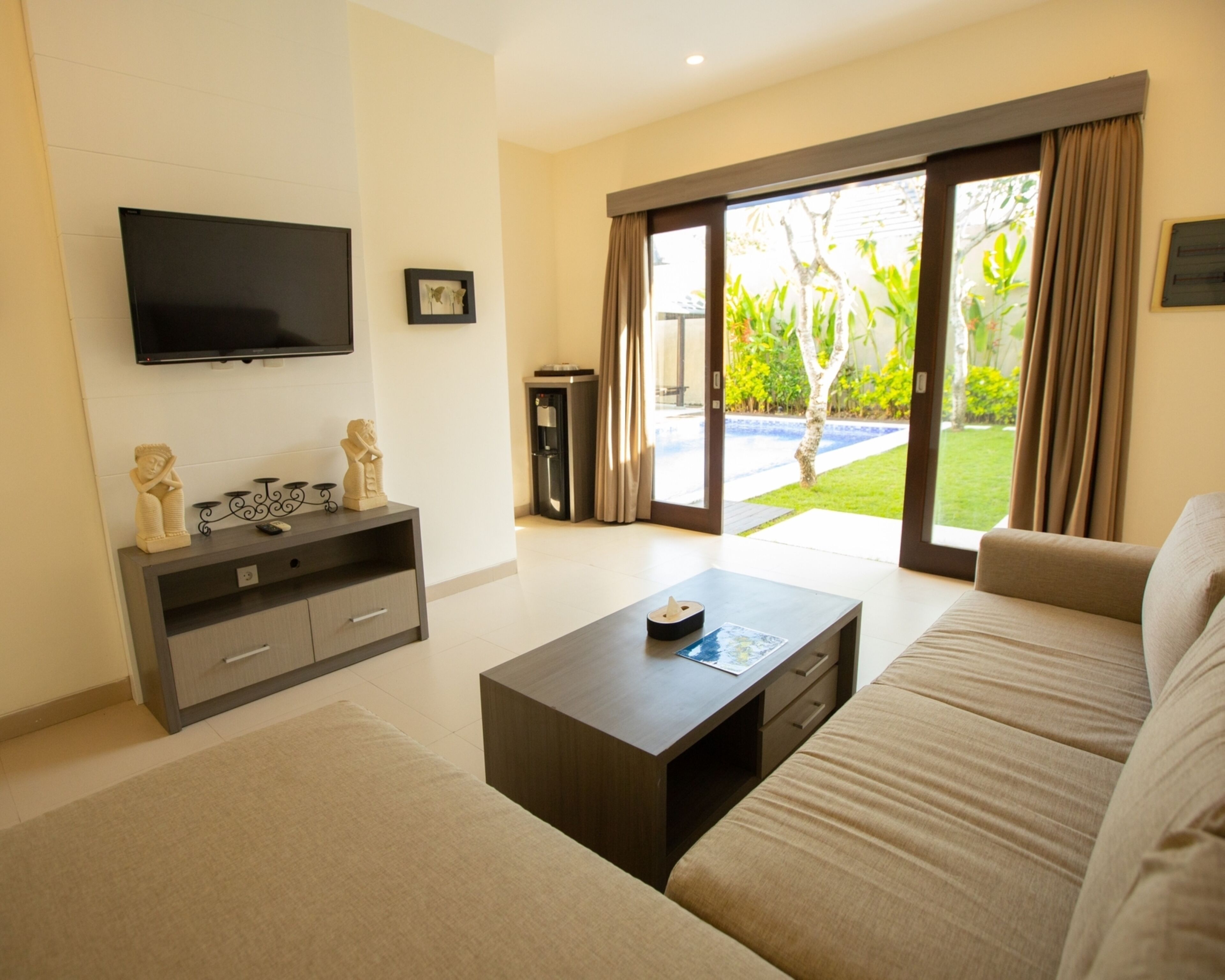 A modern living room with a sofa, coffee table, TV, and a water dispenser.